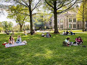 students sitting outside on grass on campus