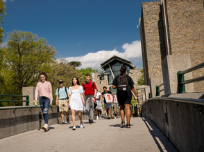 students walking outside over a bridge on campus