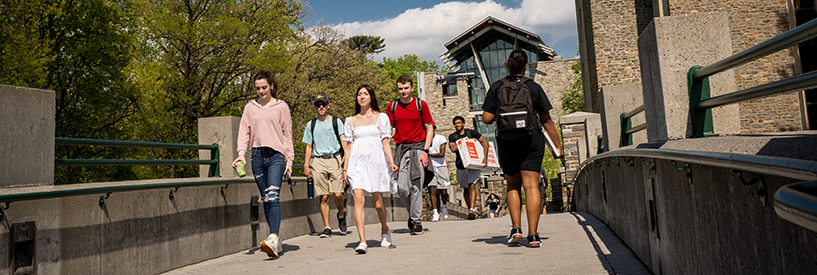 students walking outside over a bridge on campus