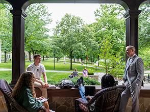 Students and faculty sitting on a porch