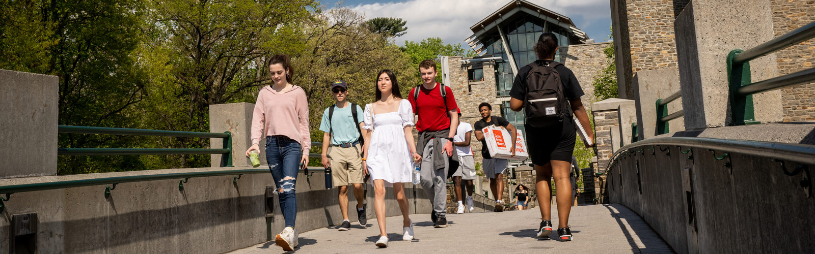 students walking outside over a bridge on campus